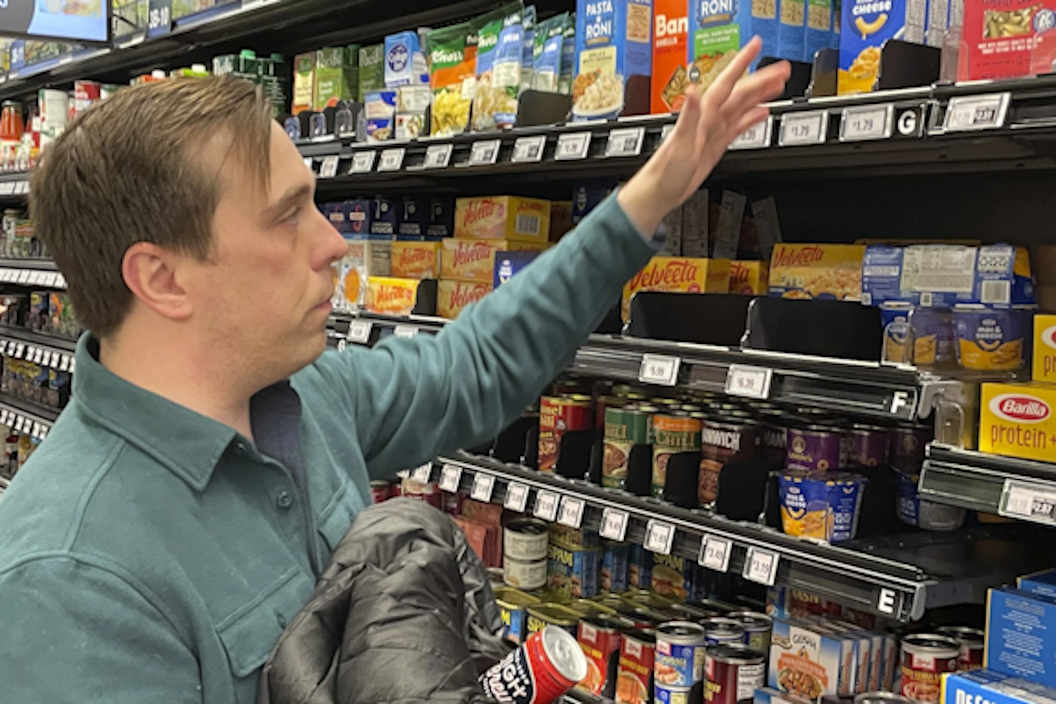 Man in grocery store reach for a box of mac and cheese
