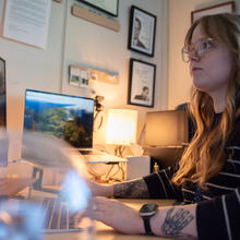 Sierra Miller sits at a desk facing a computer screen.