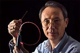 Xiao Tang of NIST's Information Technology Laboratory holding up an optical fiber channel