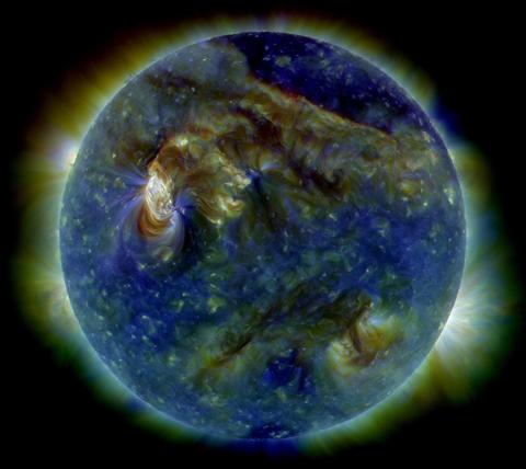 The Sun in EUV. The Sun appears mostly blue and purple with some areas of yellow. The sun is surrounded by a green/yellow corona. 