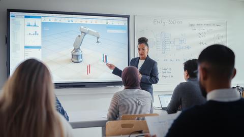 Female Professor Standing Next to Interactive Whiteboard and Teaching Diverse Students Innovations in Robotics. Computer Science and Modern Technologies in Higher Education Concept
