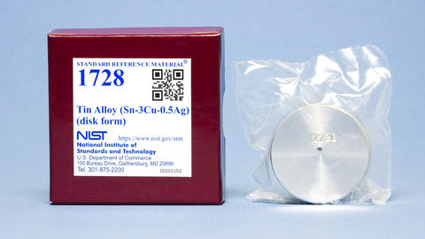 Photograph of SRM 1728 Tin Alloy showing labeled box and metallic disk.