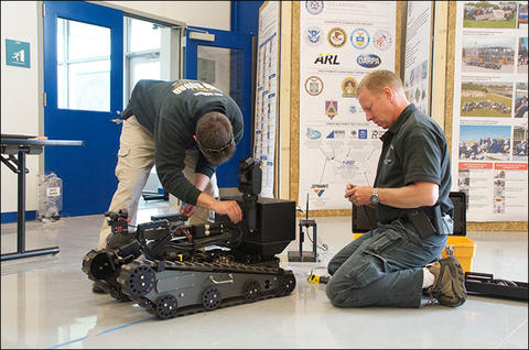 Members of the Bomb Squad make adjustments to one of the robots on the Robot Test Facility floor