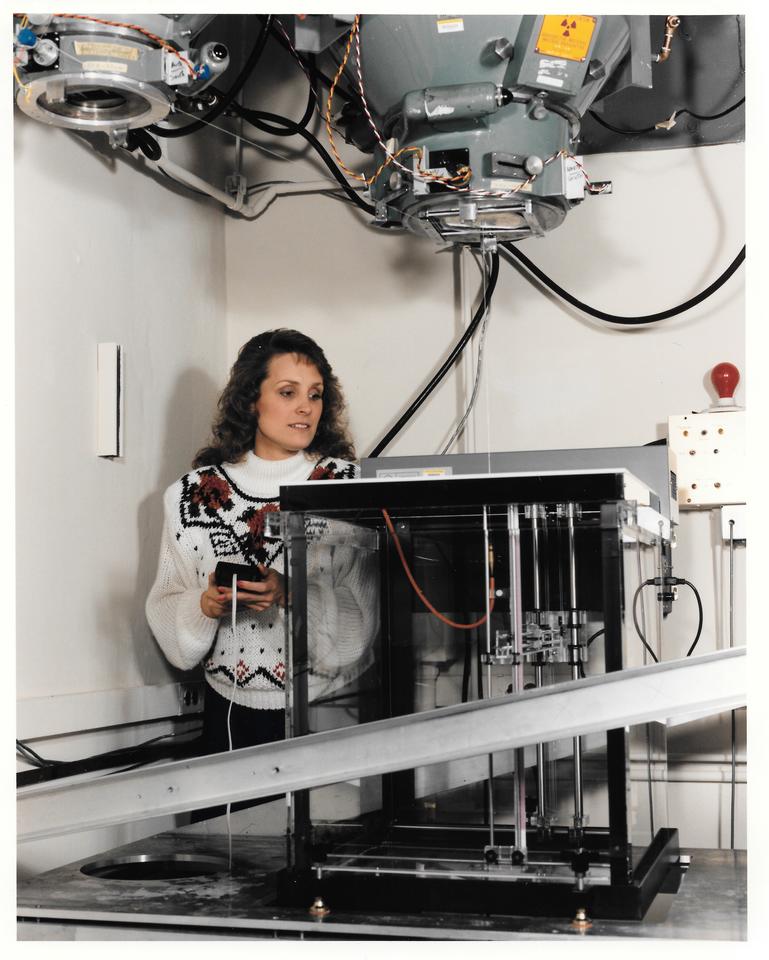 A woman adjusts a scientific device like a large box with overhead components