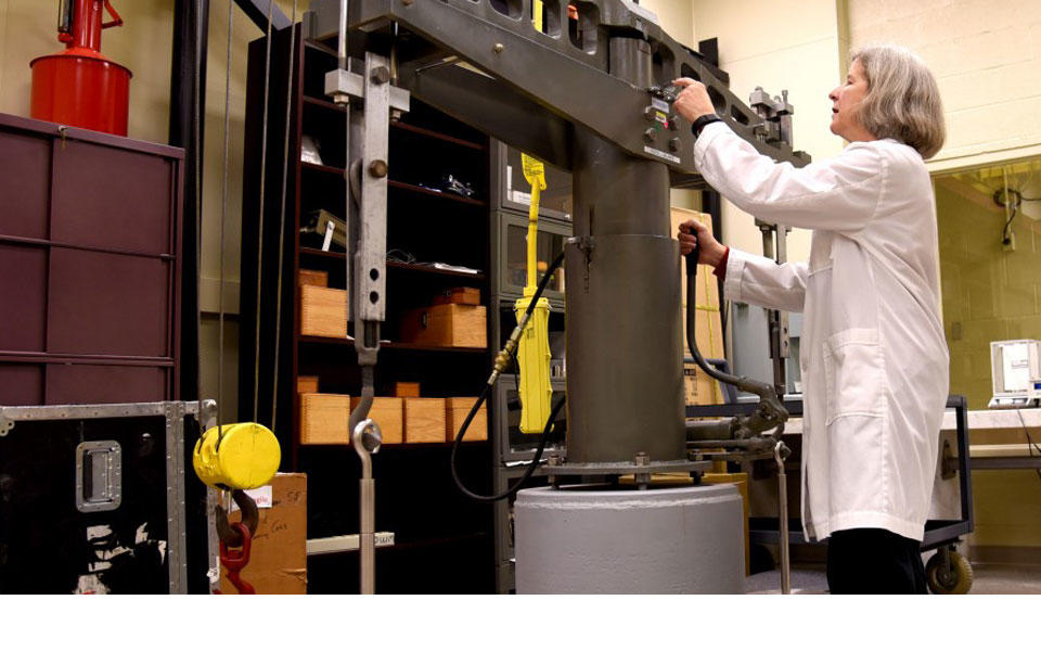 Blonde woman in white lab coat working on equipment