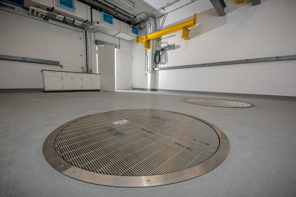 A large white room with circular metal grates in the floor.