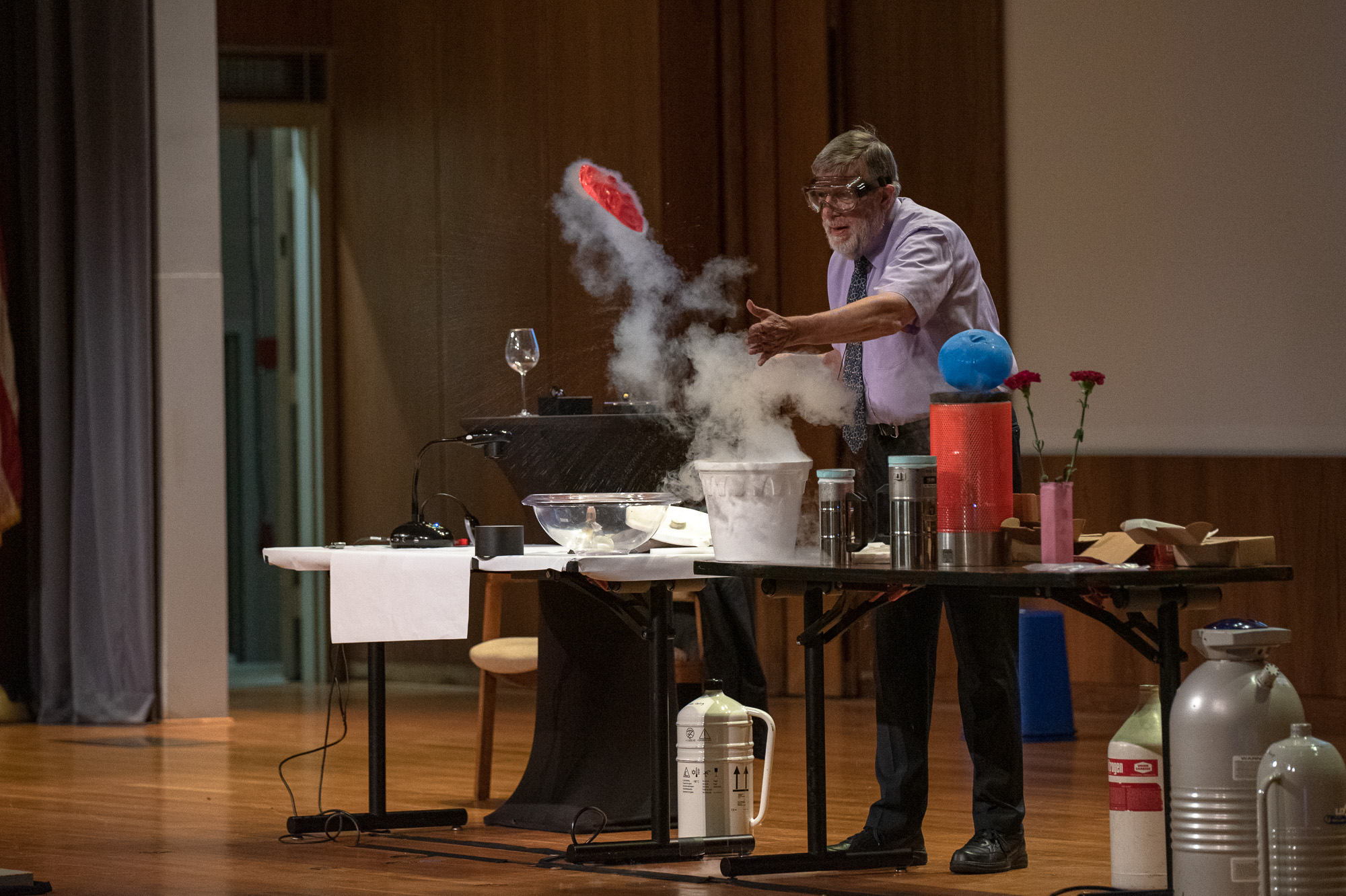 Man on a stage tossing a balloon flattened by immersing it in liquid nitrogen into the crowd