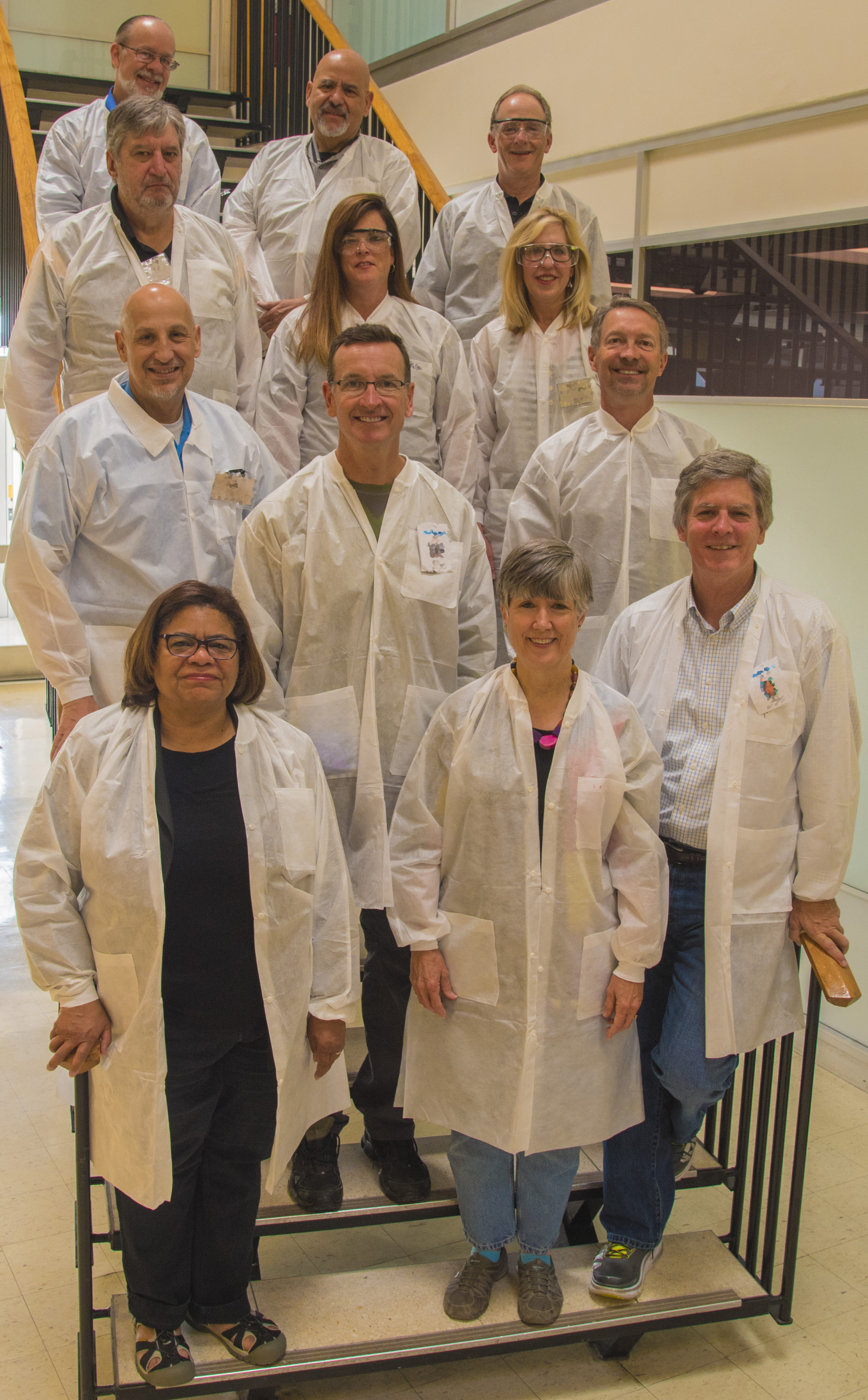 A group of student judges grouped on a flight of stairs wearing white lab coats