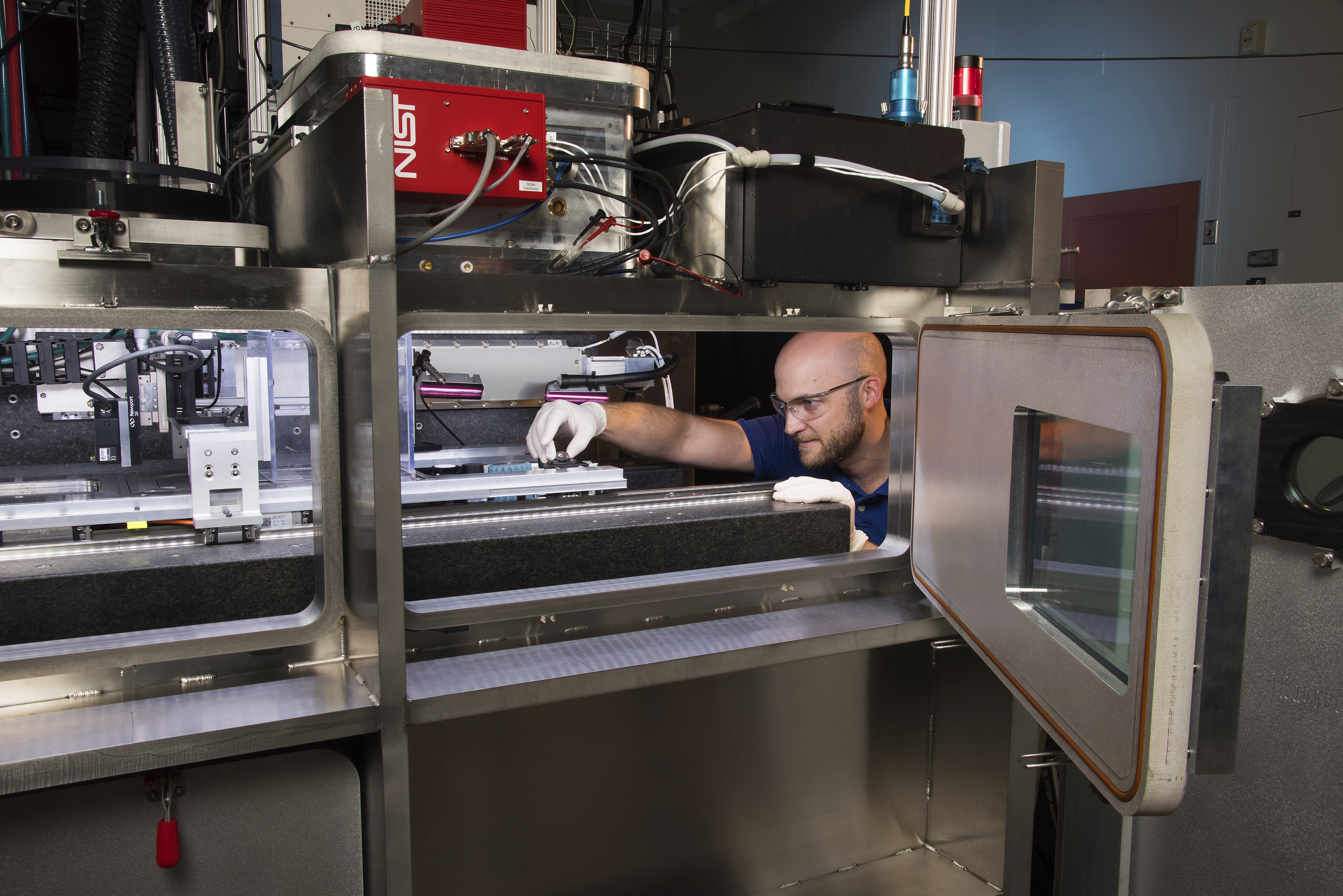 Additive Manufacturing Metrology Testbed Researcher Brandon Lane making adjustments inside the large 3D printer