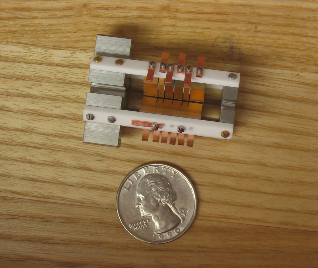 An ion trap sitting next to a quarter to show their similar size