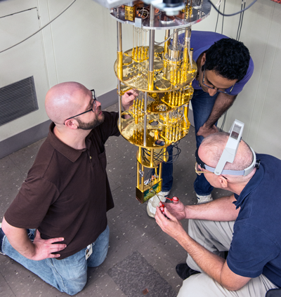 Three men hover around a piece of equipment