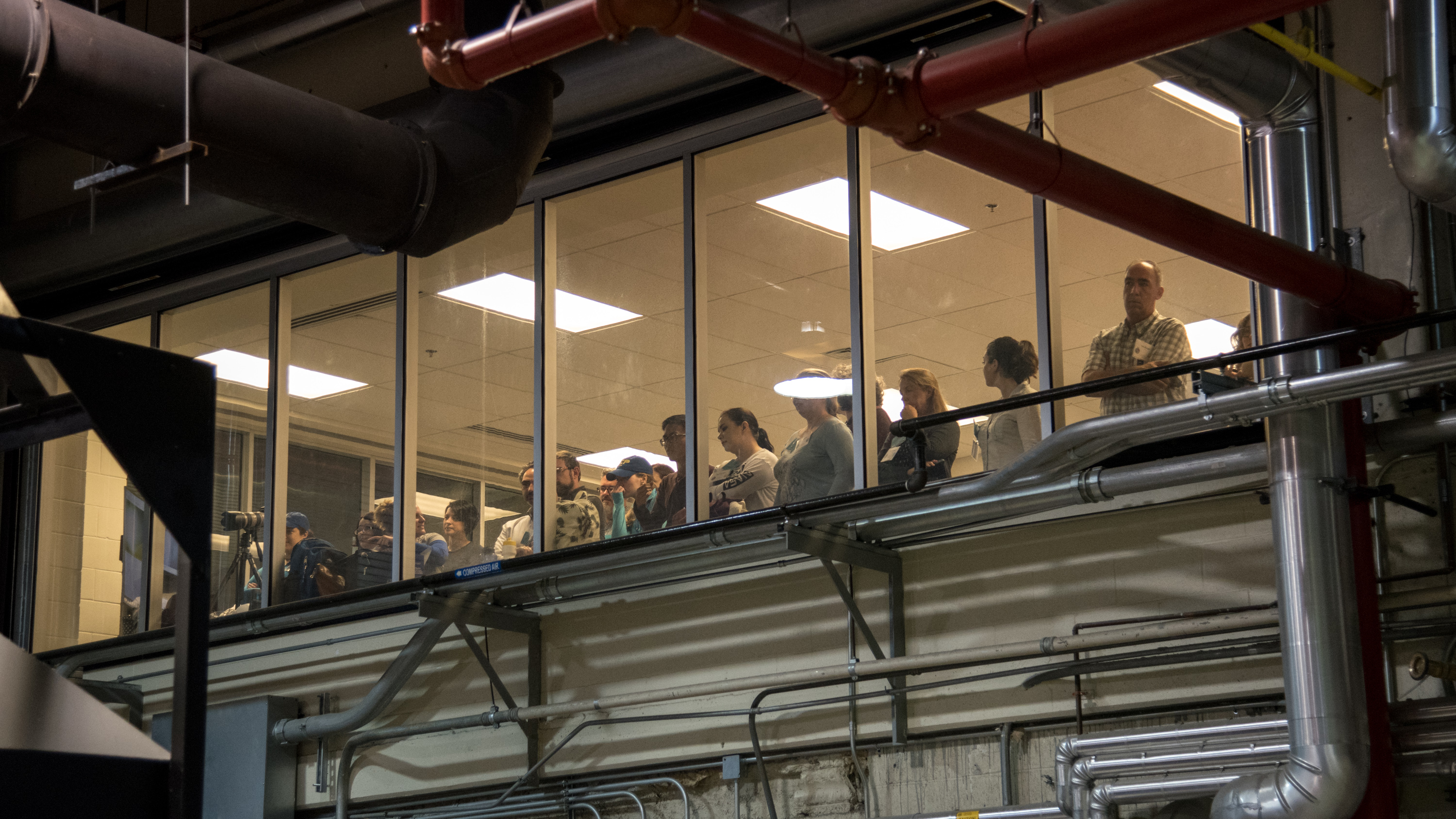 Group of people in a glass enclosed observation booth look on at the fire (out of frame)