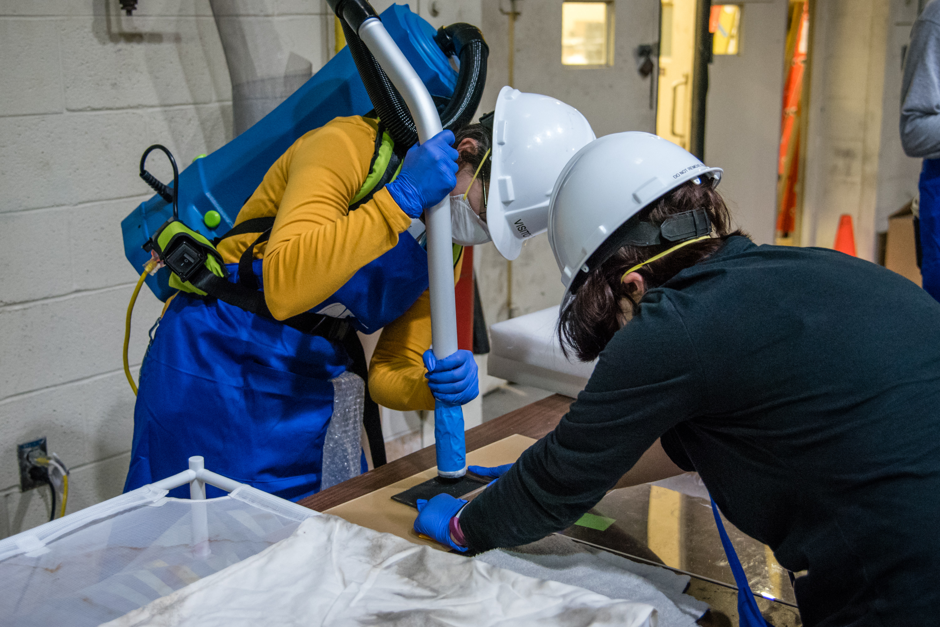 Two Smithsonian curators use a vacuum to remove water from a recovered artifact