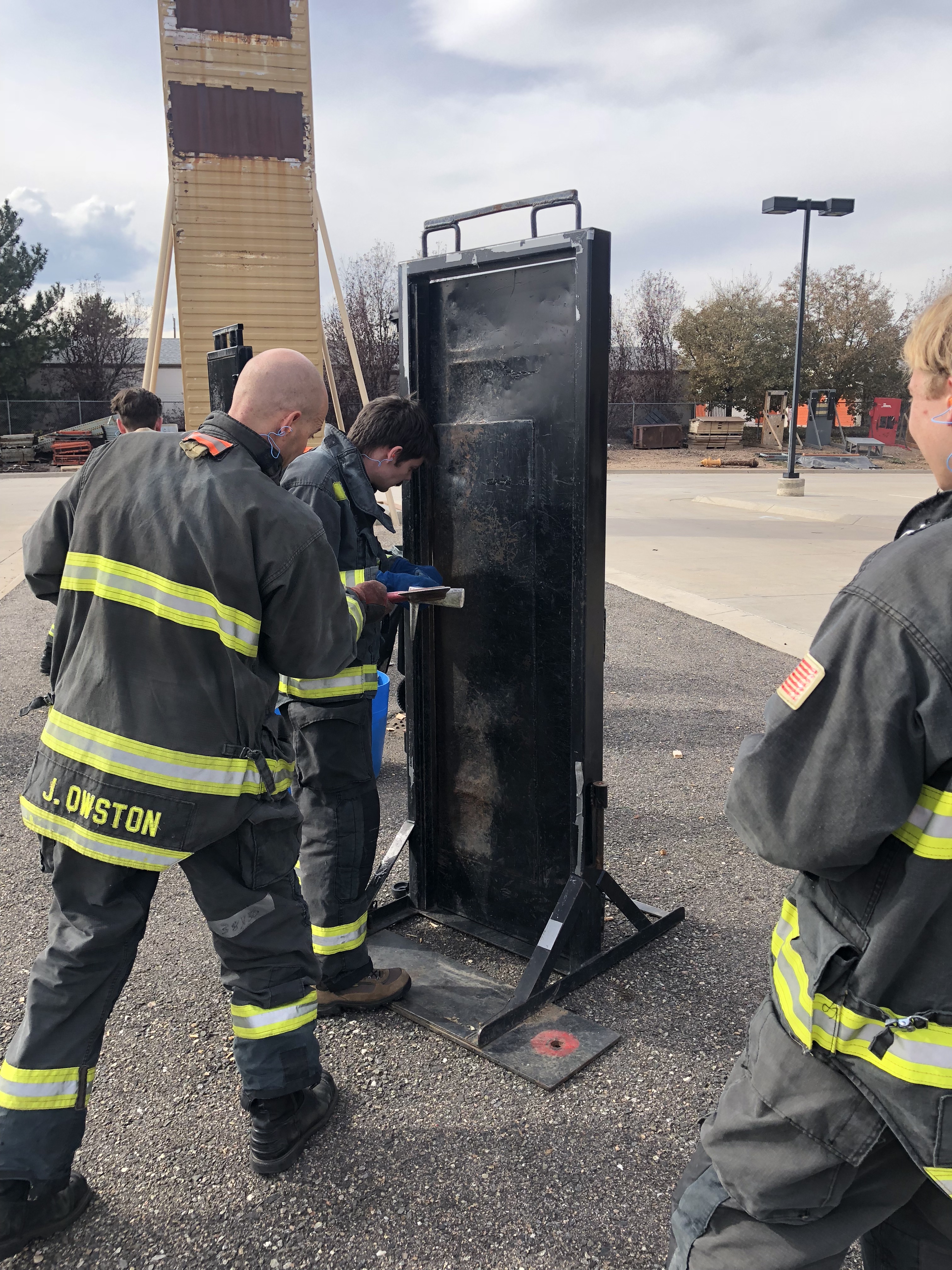 NIST firefighter trainees wait in line to try their hand at breaking down a door at the training facility