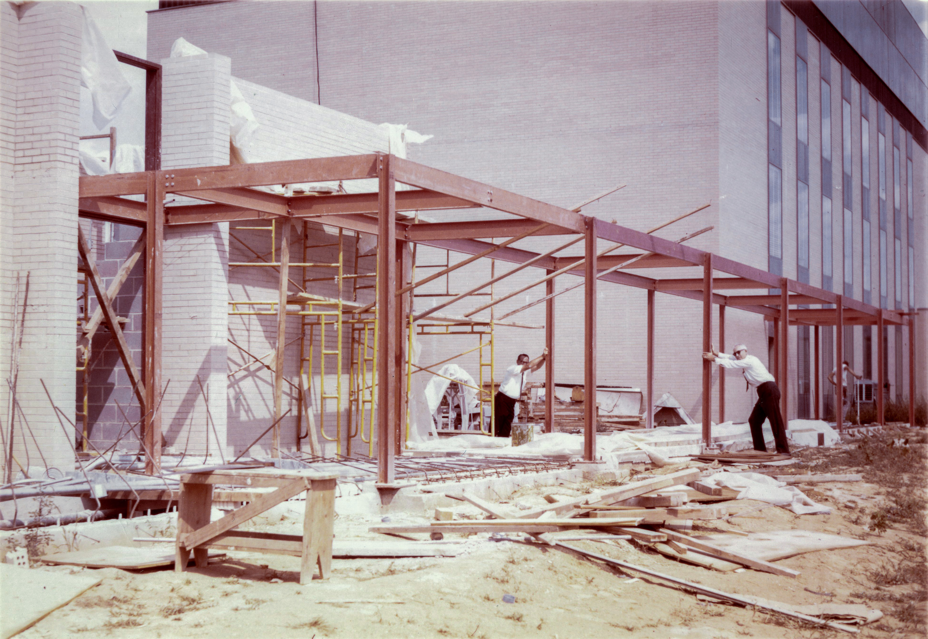 A photo showing the construction of the “breezeway” in the 1960s. Two NIST "wise guys" clown for the camera by acting as though they're keeping the structure from collapsing.