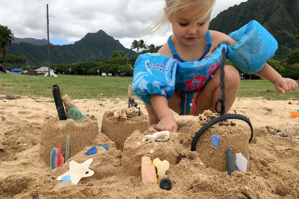 small child decorating a sandcastle with bits of plastic