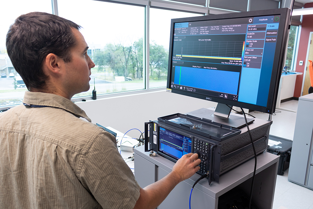 man turns a knob on a piece of equipment while looking at a monitor