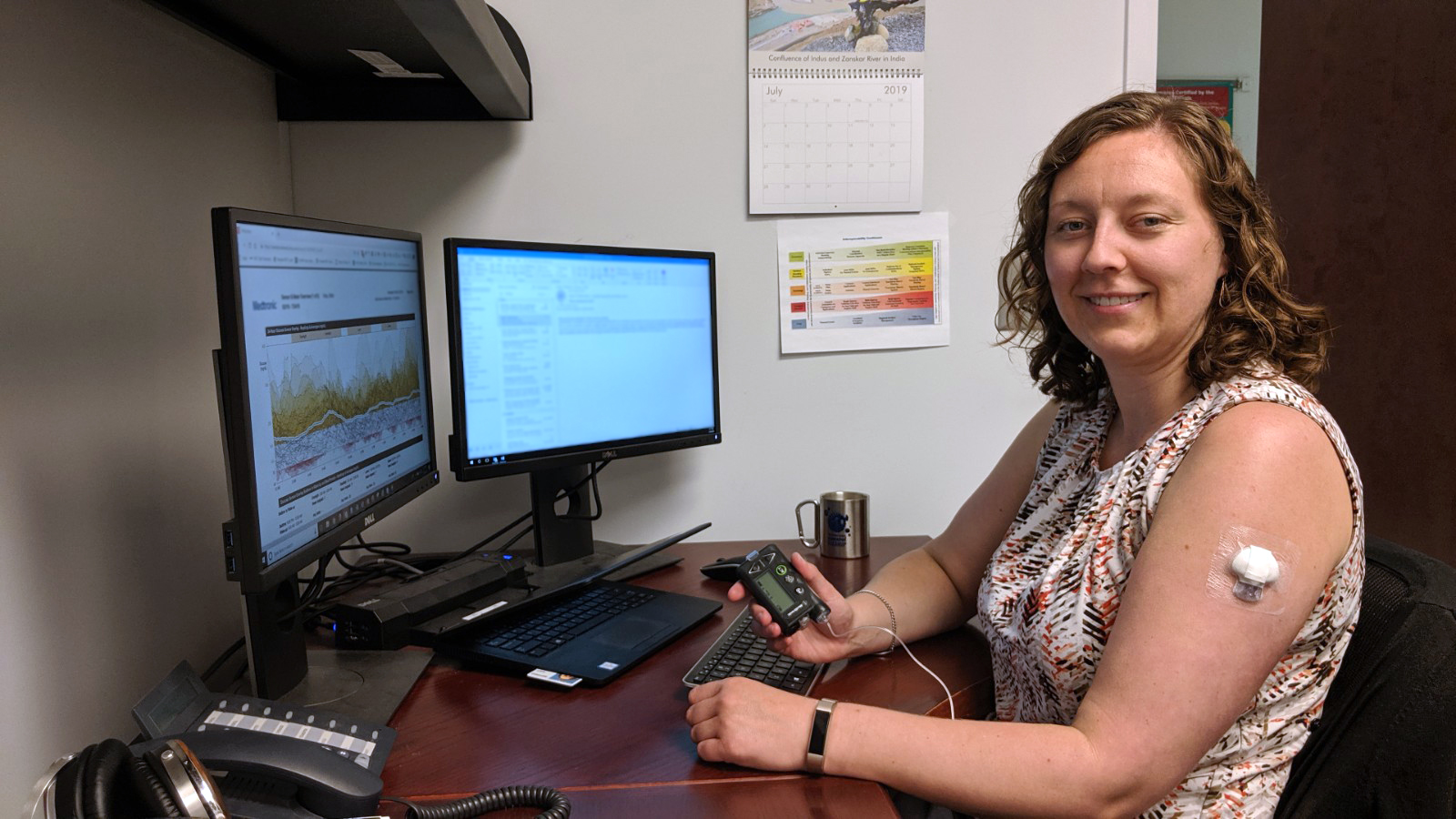 Britta Voss poses with her insulin pump in her office. 