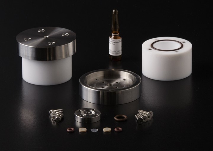 Components of NIST prototype formaldehyde emission reference material. Two white cylinders, two steel endcaps, screws, washers, and membranes