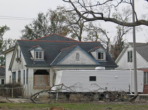 two trailer homes parked on the front lawns of houses damaged by Hurricane Katrina.