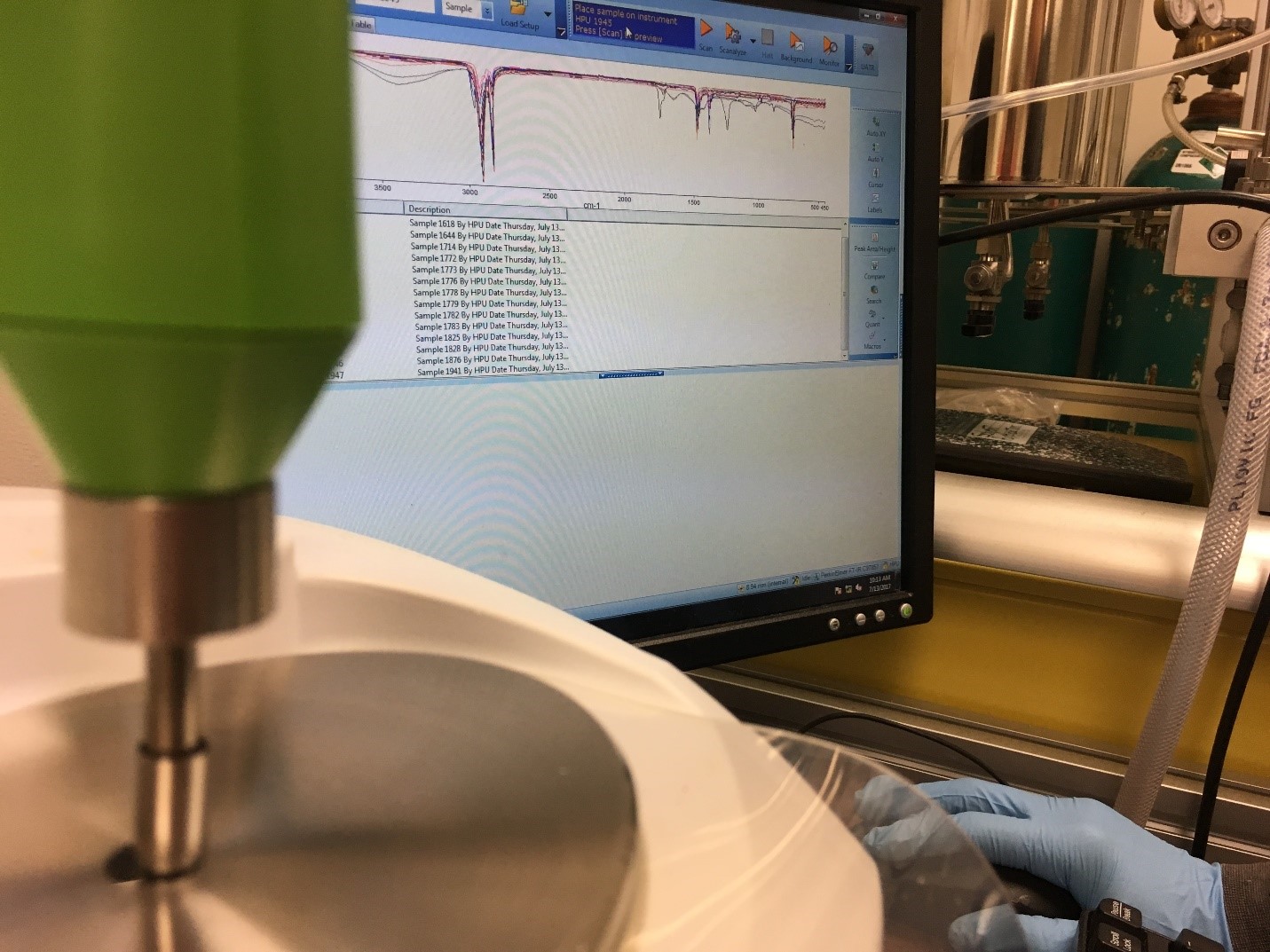 Photograph of an analytical instrument and a computer monitor displaying an FT-IR spectrum.