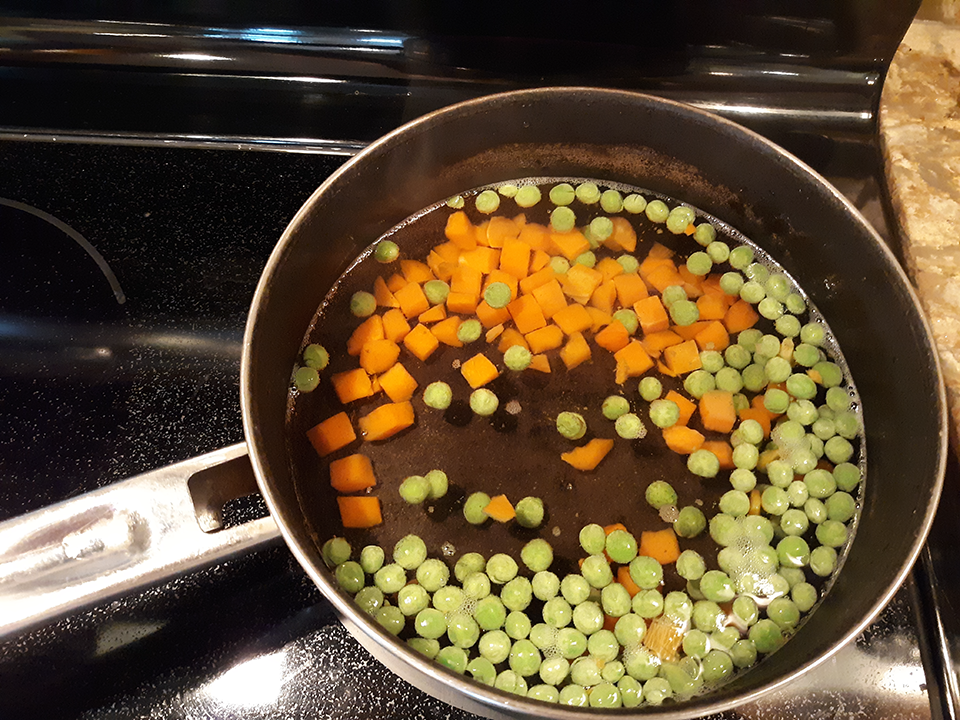 Peas and carrots 256 s after initiation of heat. The peas are  oating on the lower right half of the pan while the carrots are not  oating and are in the upper left of the pan. Temperature, as measured with an optical thermometer, is approximately 70 C.