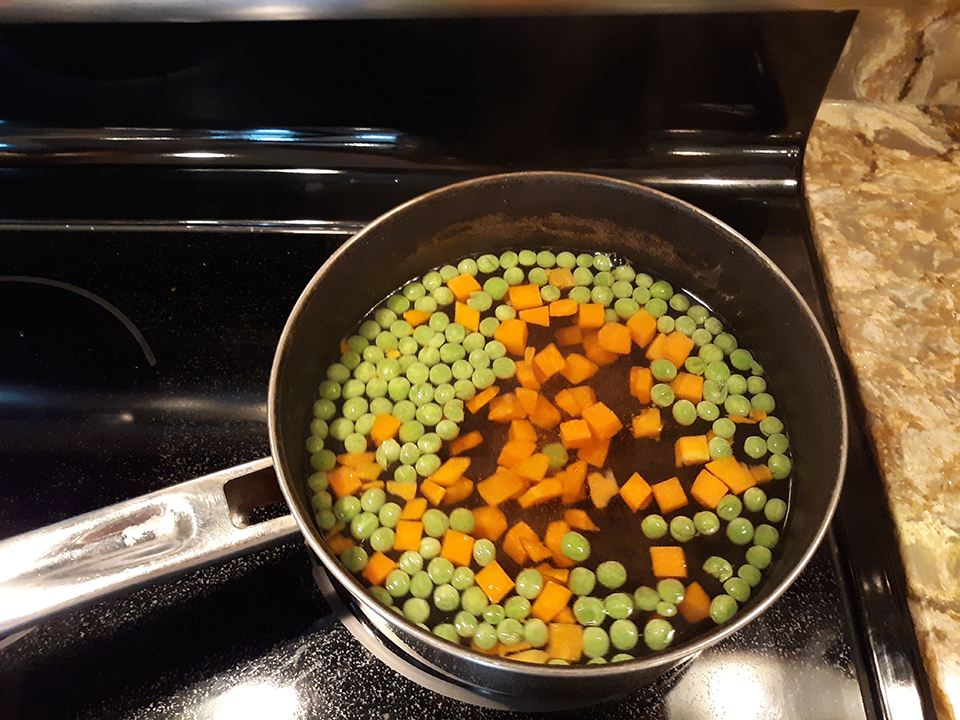 Peas and carrots 323 seconds after initiation of heat. The temperature is approximately 80 C (176 F). The peas have moved about 150 degrees clockwise while the carrots are mostly in the center. A few carrots have begun to float and are mixed with the peas.