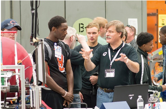 Teenagers listening attentively as the senior engineer explains about machine. 