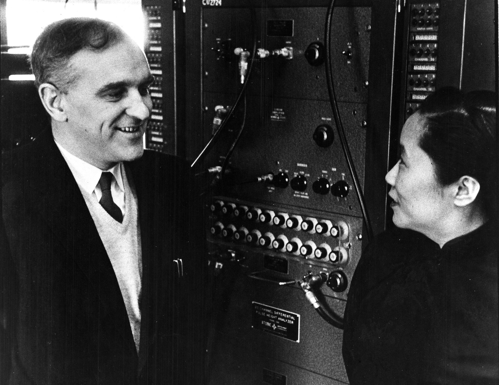 Ernest Ambler and Chien-Shiung Wu in front of a control panel 