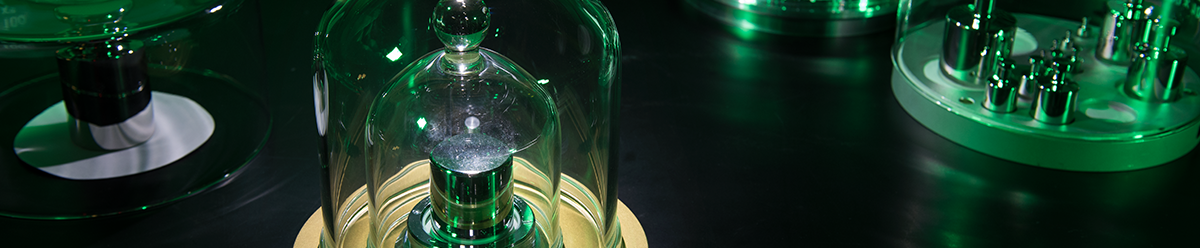 Black background. Green lighting. Kilograms under glass domes.