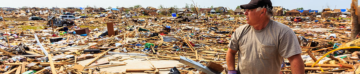 Man standing among the wreckage of homes.