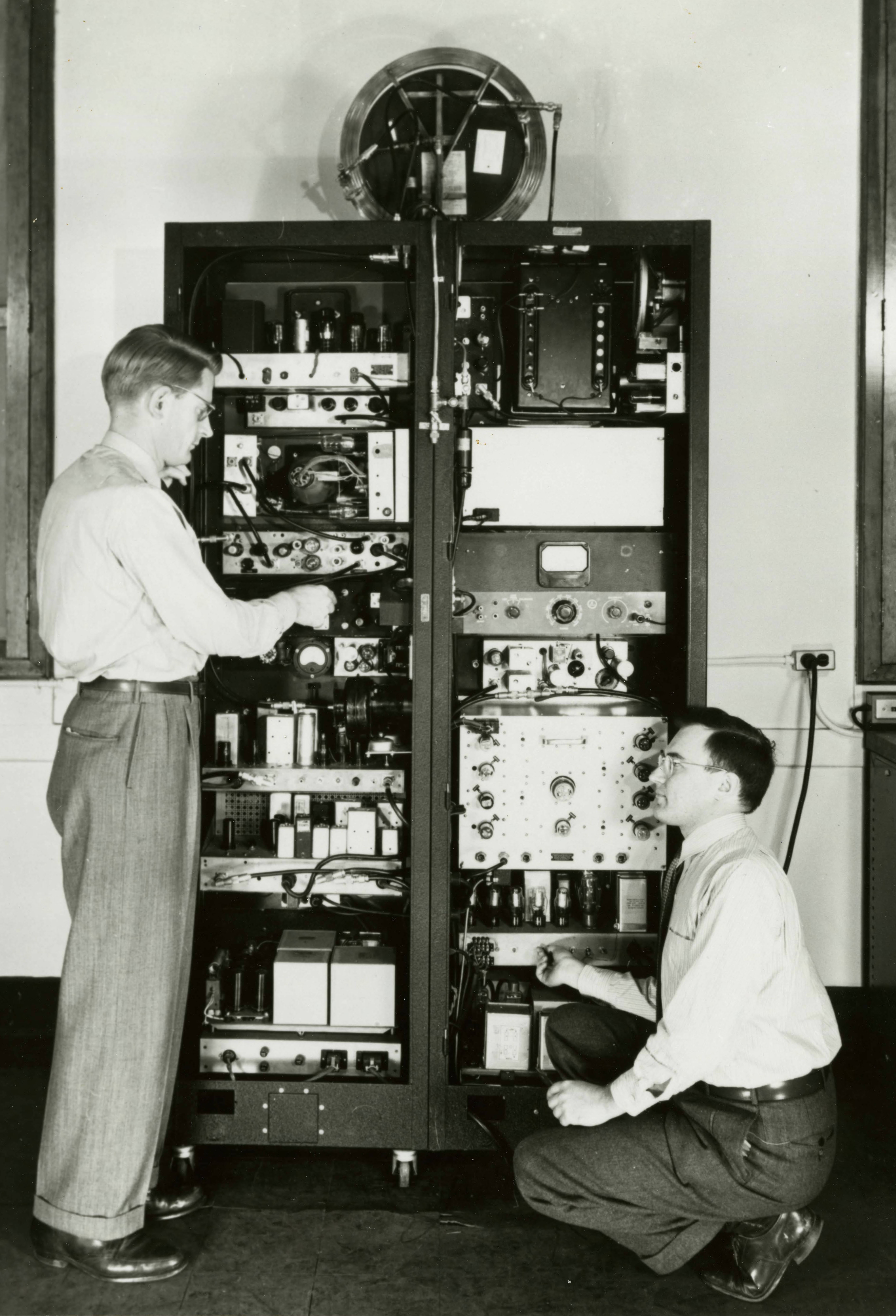 Photograph of Benjamin F. Husten and Emory D. Heberling adjusting the first NBS Atomic Clock, circa 1949.