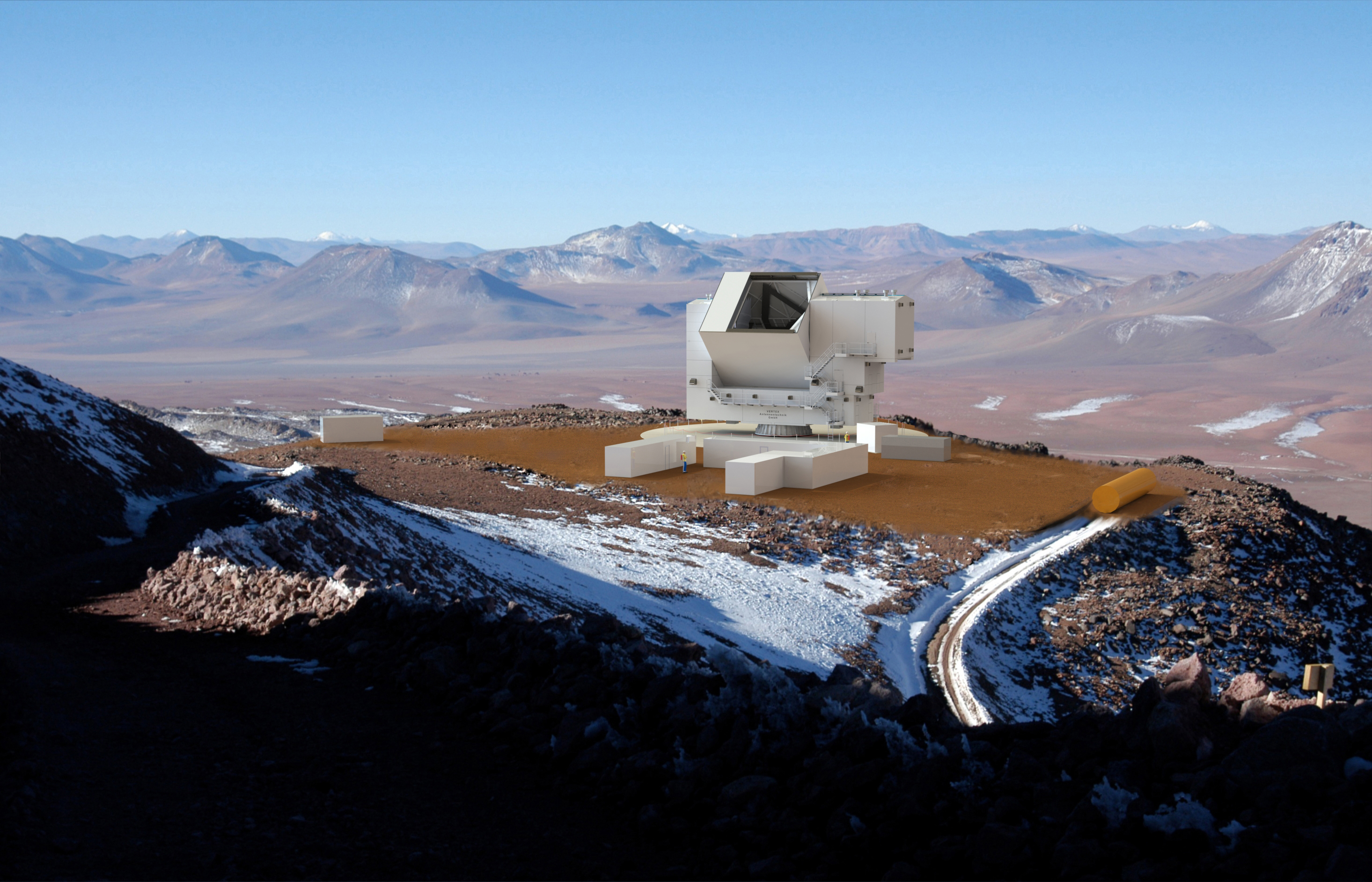 A blocky white building sits in the desert surrounded by mountains. 