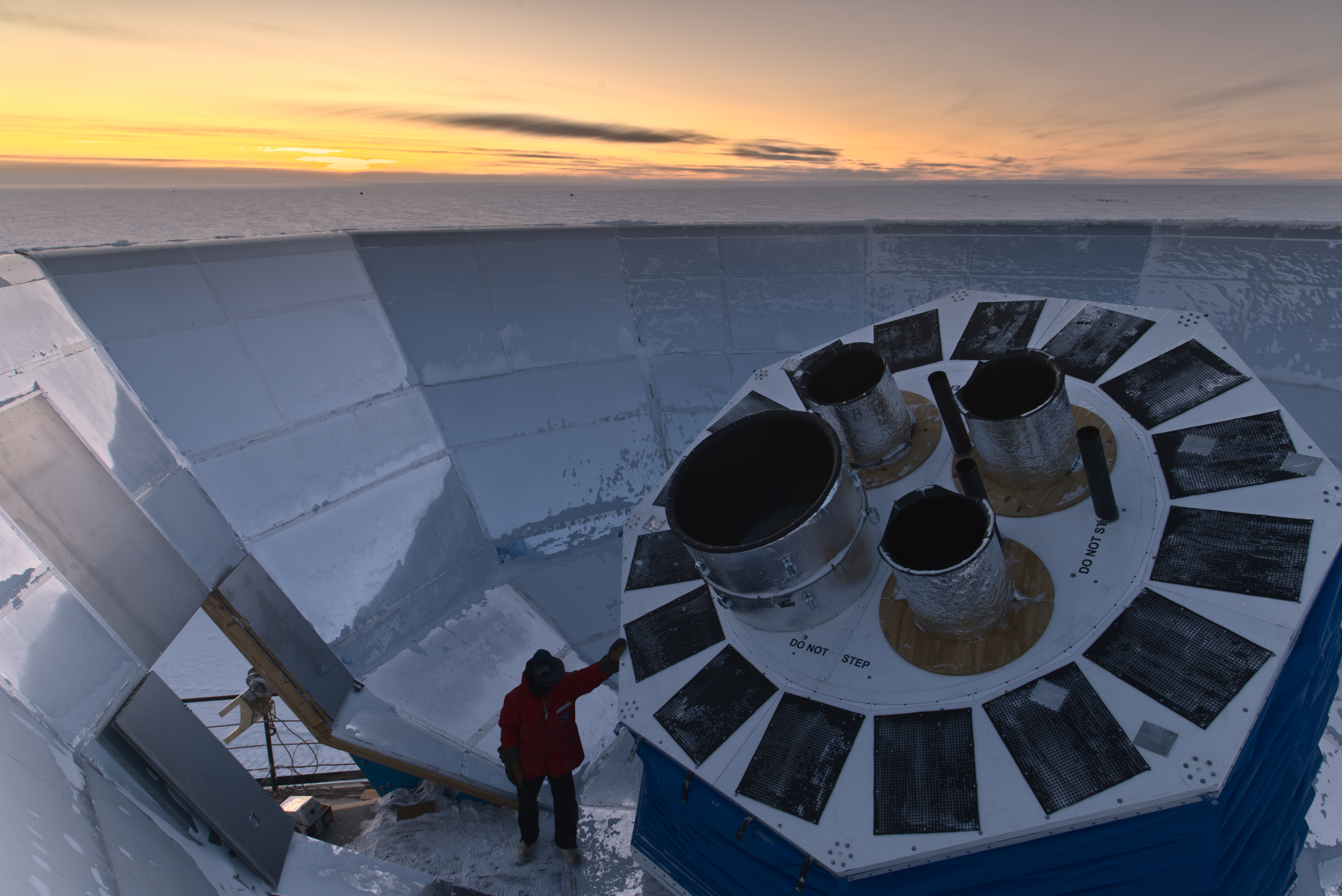 Four cylinders emerge from a circular structure inside a large dish, with a snowy landscape behind. 