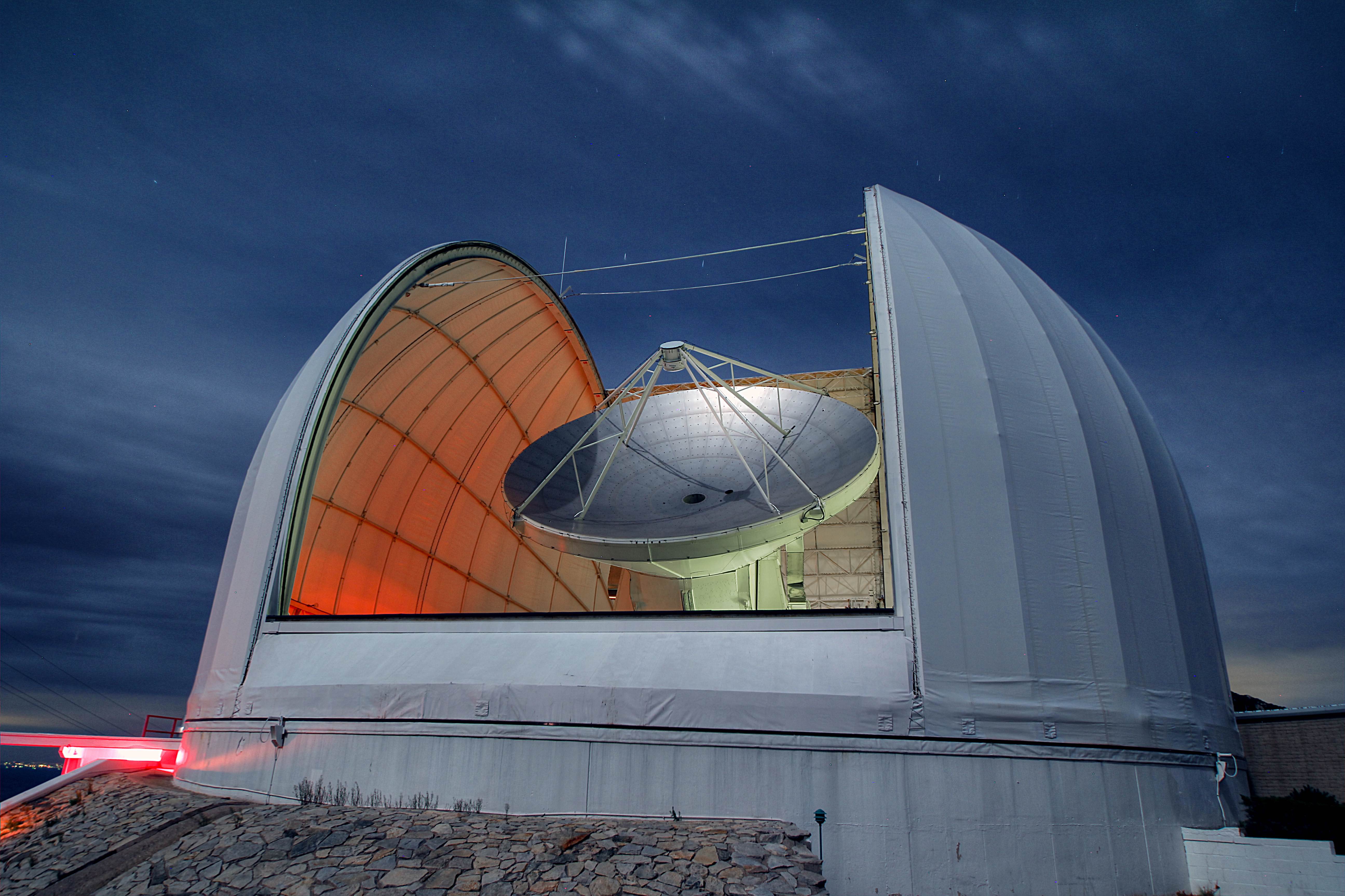 Large dish points up to the sky inside open observatory structure .