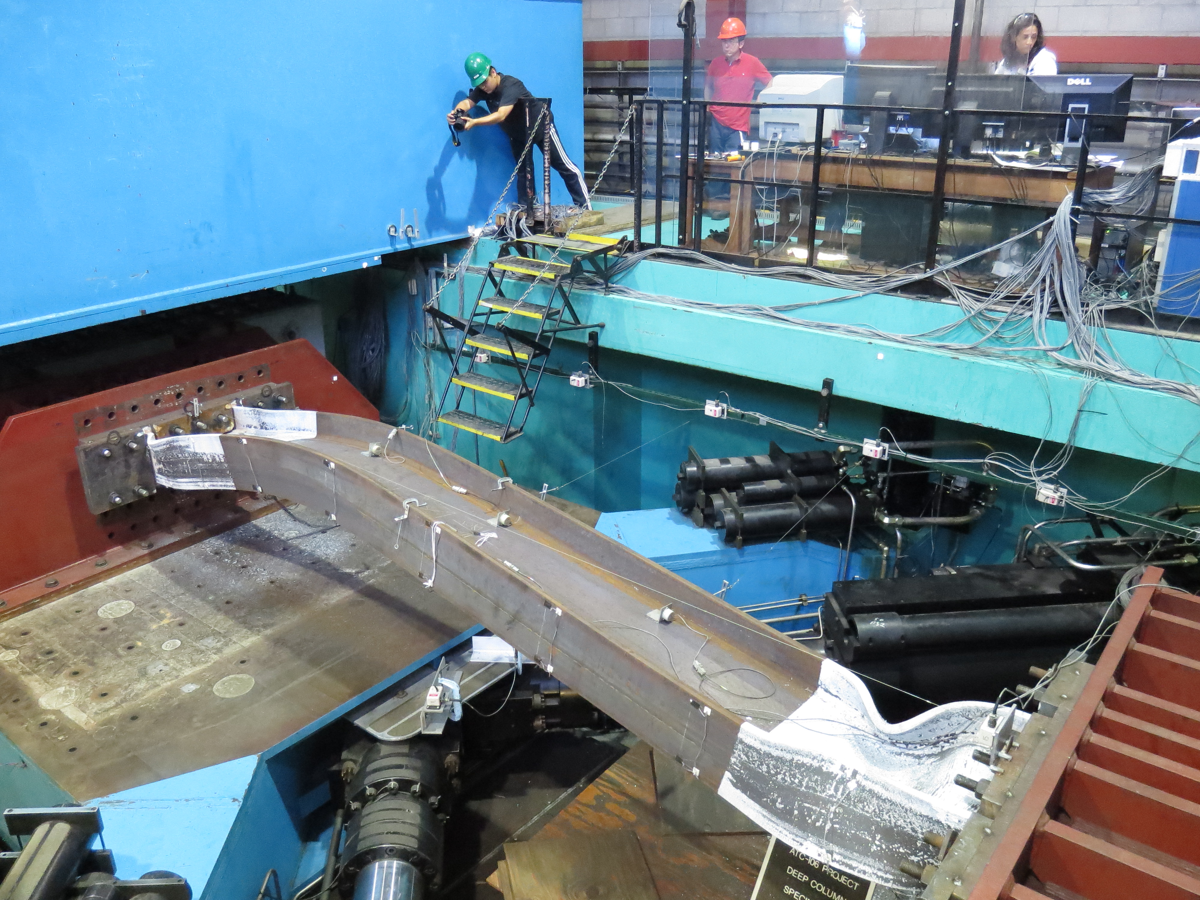 A metal column being twisted by a seismic testing machine as researchers look on.