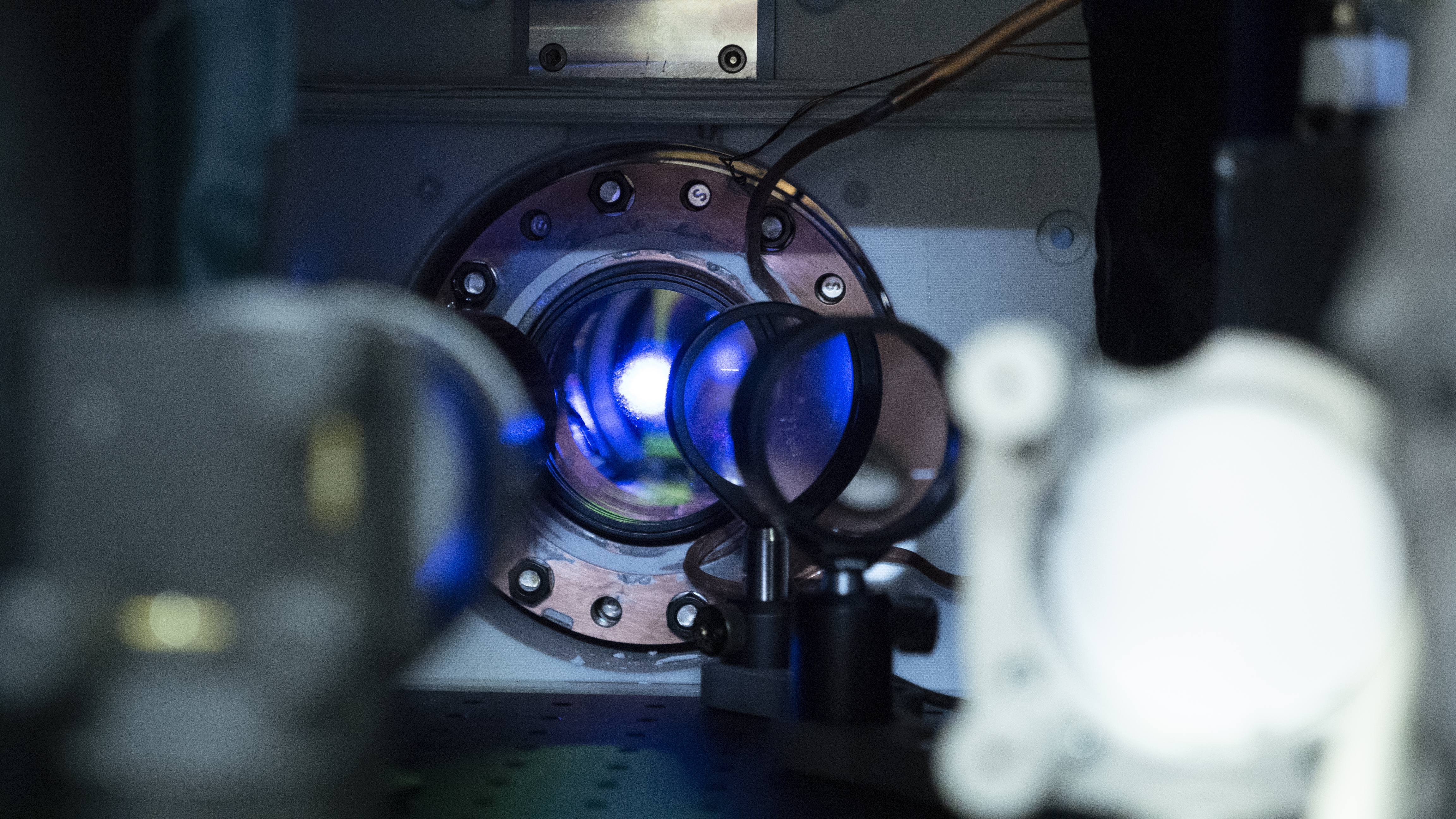 Blue light shines out of a circular opening in an atomic clock. 
