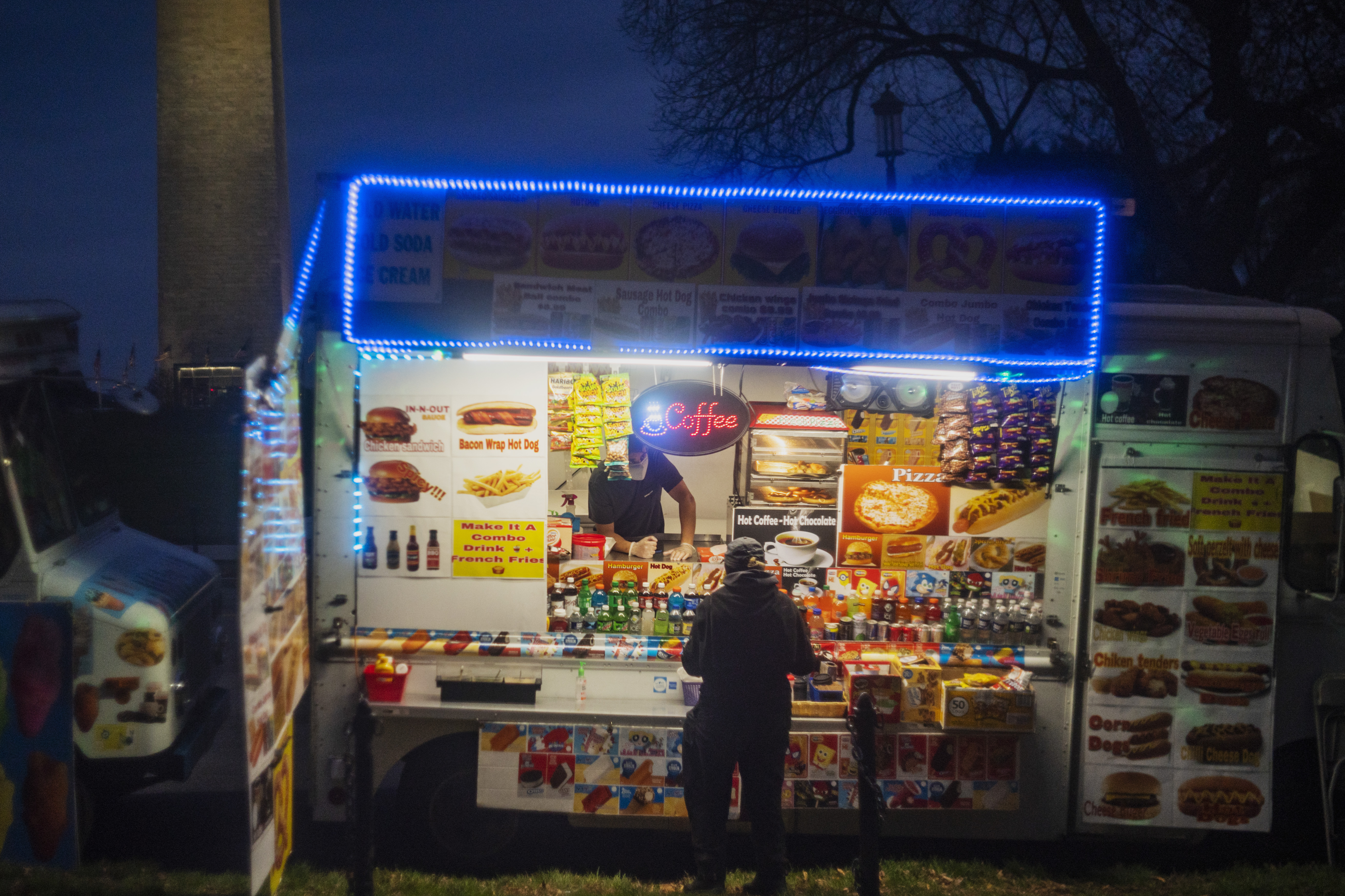 A person works inside a food truck near the Washington Monument at night.