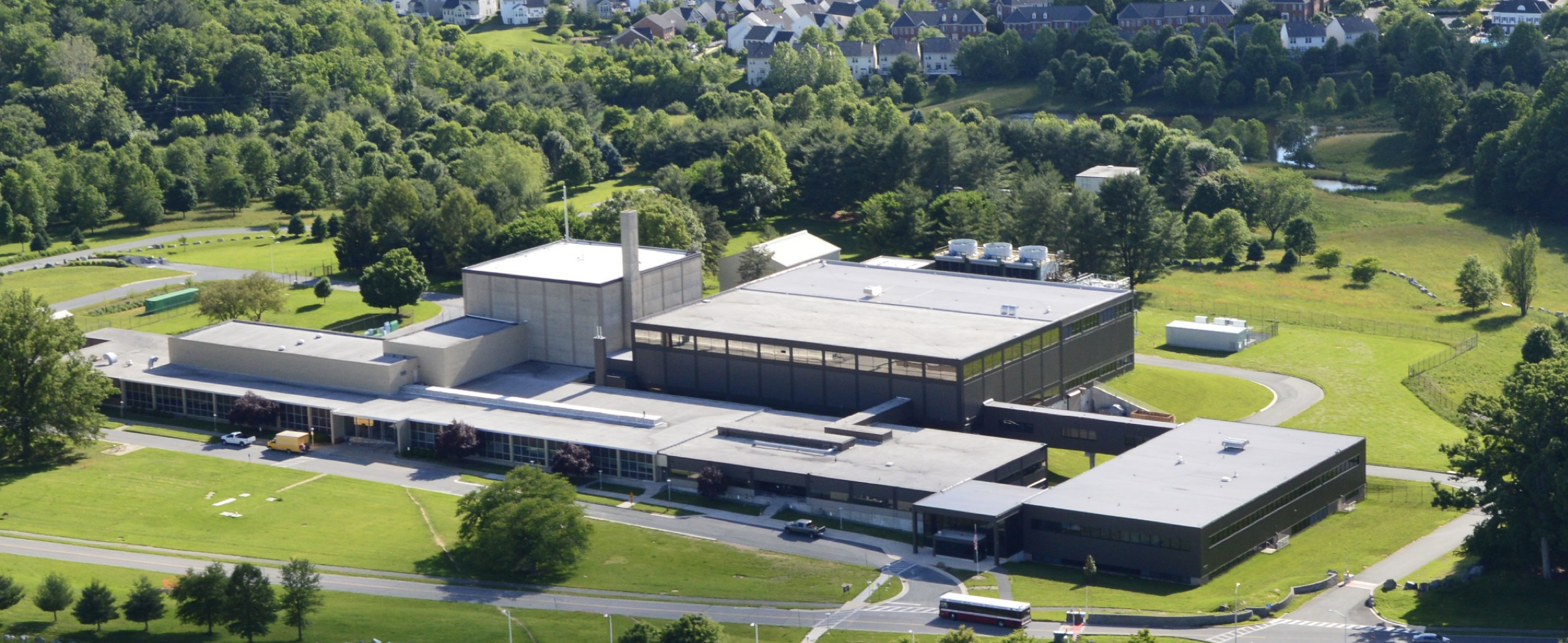 View from above shows NIST's Center for Neutron Research building with green lawns and trees.