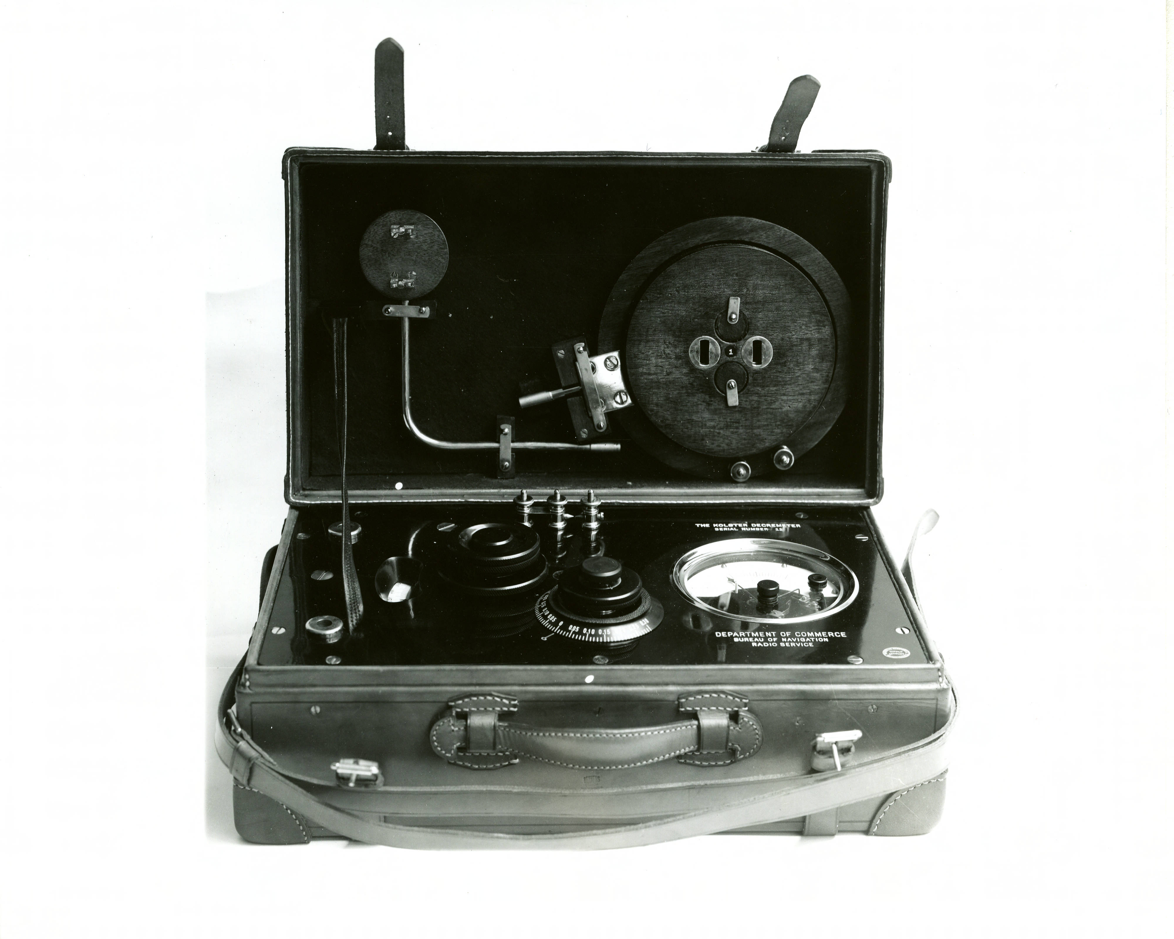 Historical photo shows scientific device in an open case, with dials and receivers.