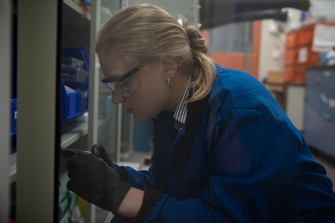 Christine McGinn wears safety glasses as she bends over her work in the lab. 