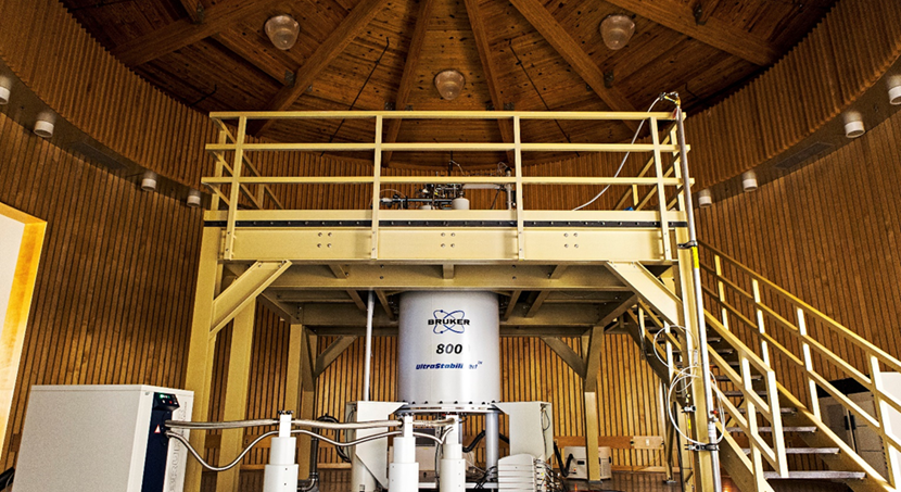 Photograph of nuclear magnetic resonance facility with liquid helium cooled magnet and stairway access to autosampler device. 