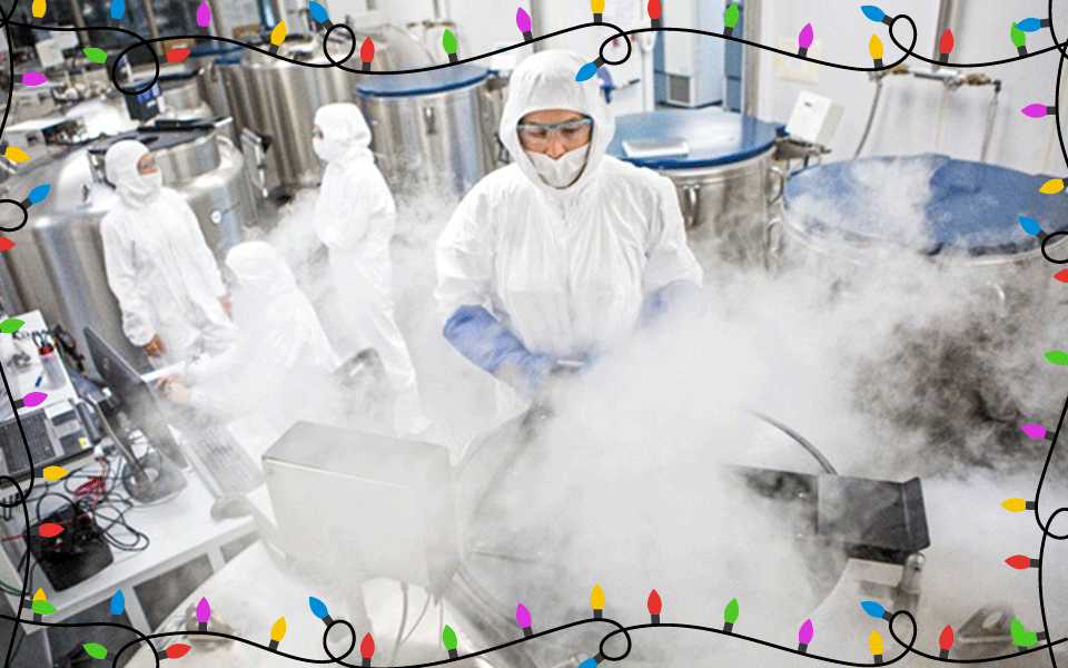 A researcher in a white coverall stands over a metal container with freezing vapor floating out in a lab lined with similiar containers. 