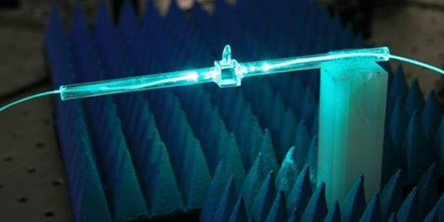 A glowing blue cylindrical rod has fibers coming out of either end. 
