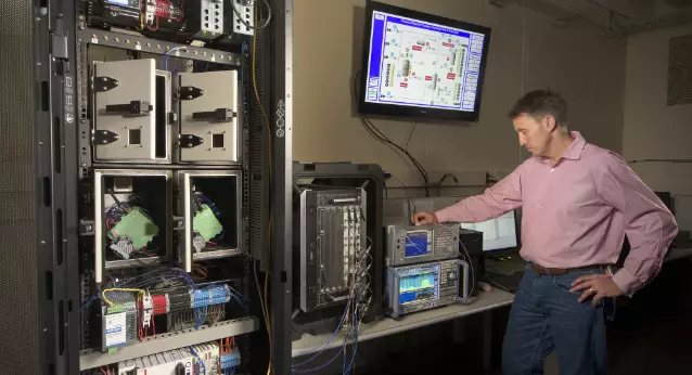 Male in pink shirt looking at scientific device