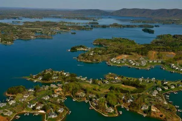 An aerial view of a lake shows homes built along its winding shores.