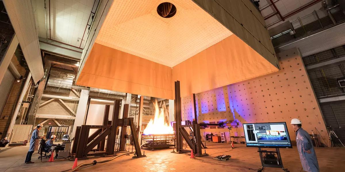 Photograph of large open room with fire engineers standing around a large fire test.