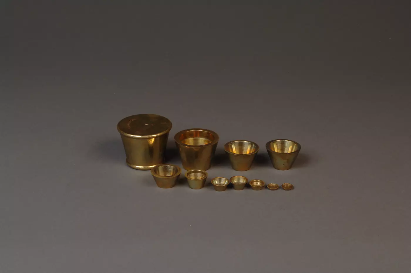 11 gold weights on a gray background