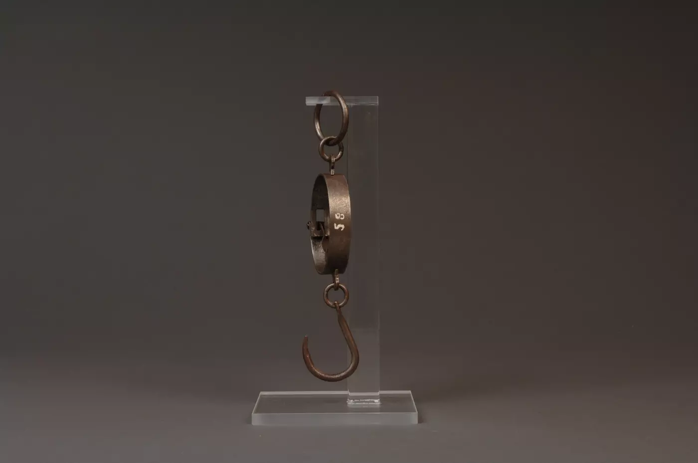 Side view of steel mancur balance hanging from clear plastic stand