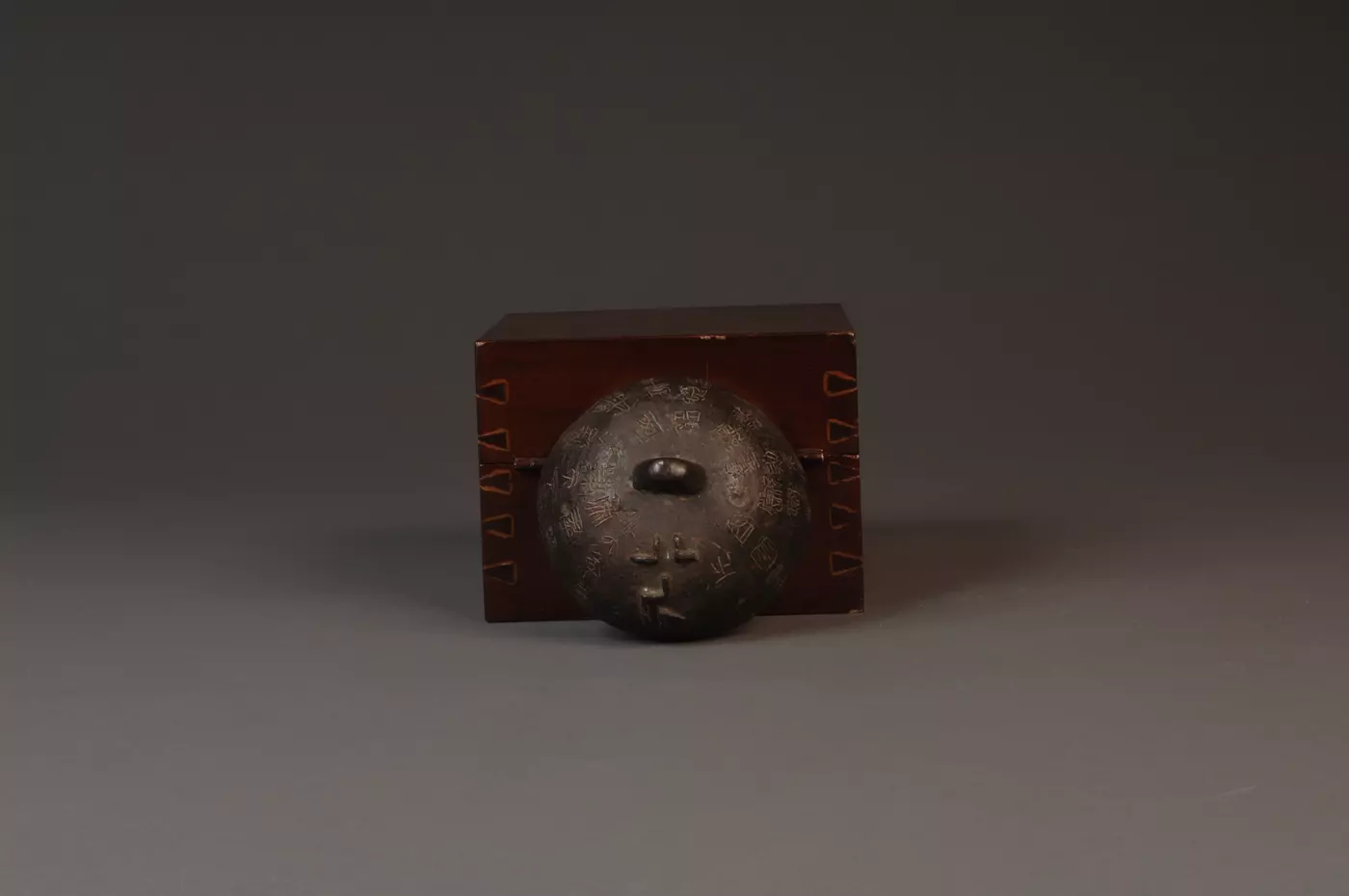 Bronze weight with Chinese writing in front of accompanying box